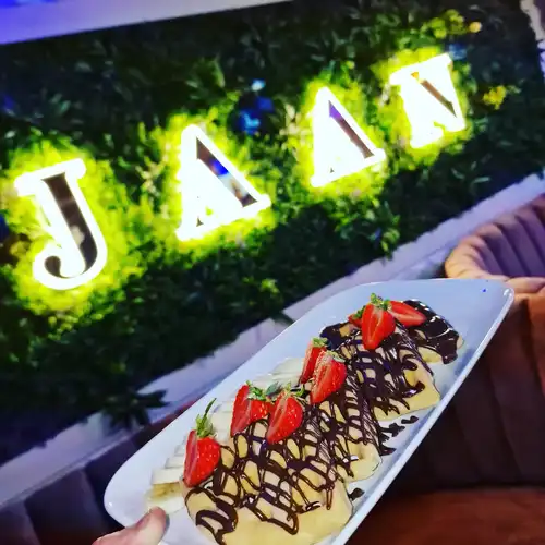 Ice cream with choclate spread on the top behind it Jaan Lounge branding on the grass wall behind